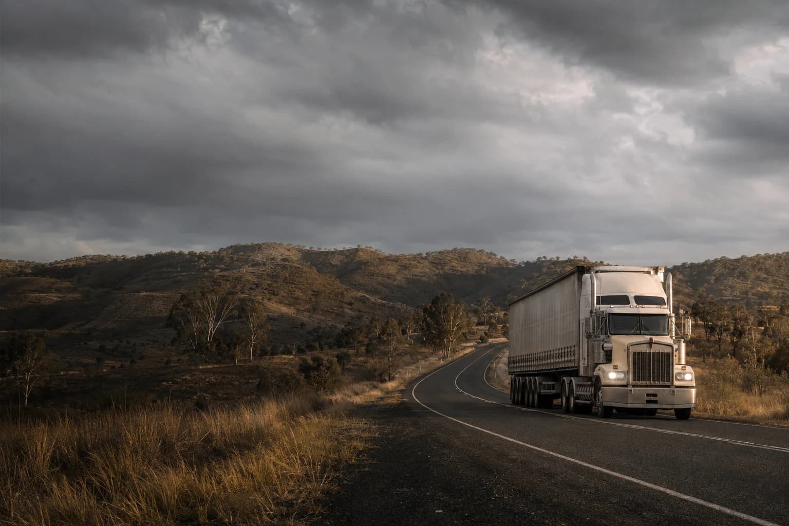 Truck following a winding rural road through open Australian country